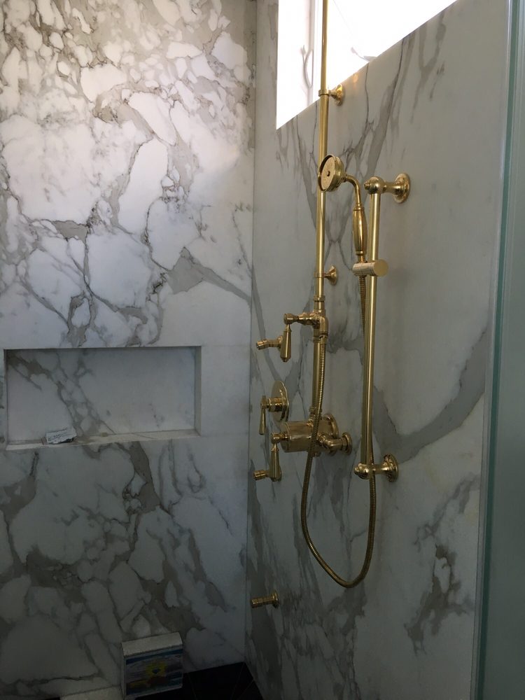 Luxury gold shower fixture installation in a marble Orlando bathroom